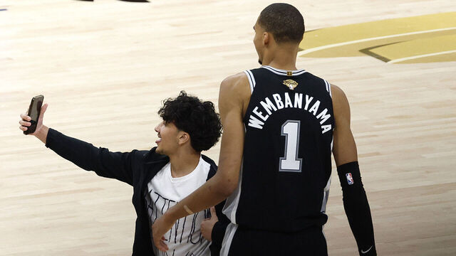 SAN ANTONIO, TEXAS - JUNE 03: A fan runs onto the court and takes a photo with Victor Wembanyama #1 of the San Antonio Spurs during the fourth quarter in Game One of the 2026 NBA Finals against the New York Knicks at Frost Bank Center on June 03, 2026 in San Antonio, Texas.