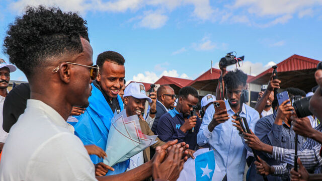 MOGADISHU, SOMALIA - JUNE 09: Somali referee Omar Abdulkadir Artan, draped in the Somali flag, is surrounded by fans following his arrival in Mogadishu, Somalia, on June 09, 2026. Artan returned to the country after being denied entry to the United States.