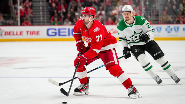 DETROIT, MICHIGAN - DECEMBER 23: Dylan Larkin #71 of the Detroit Red Wings skates with the puck against Roope Hintz #24 of the Dallas Stars at Little Caesars Arena on December 23, 2025 in Detroit, Michigan.