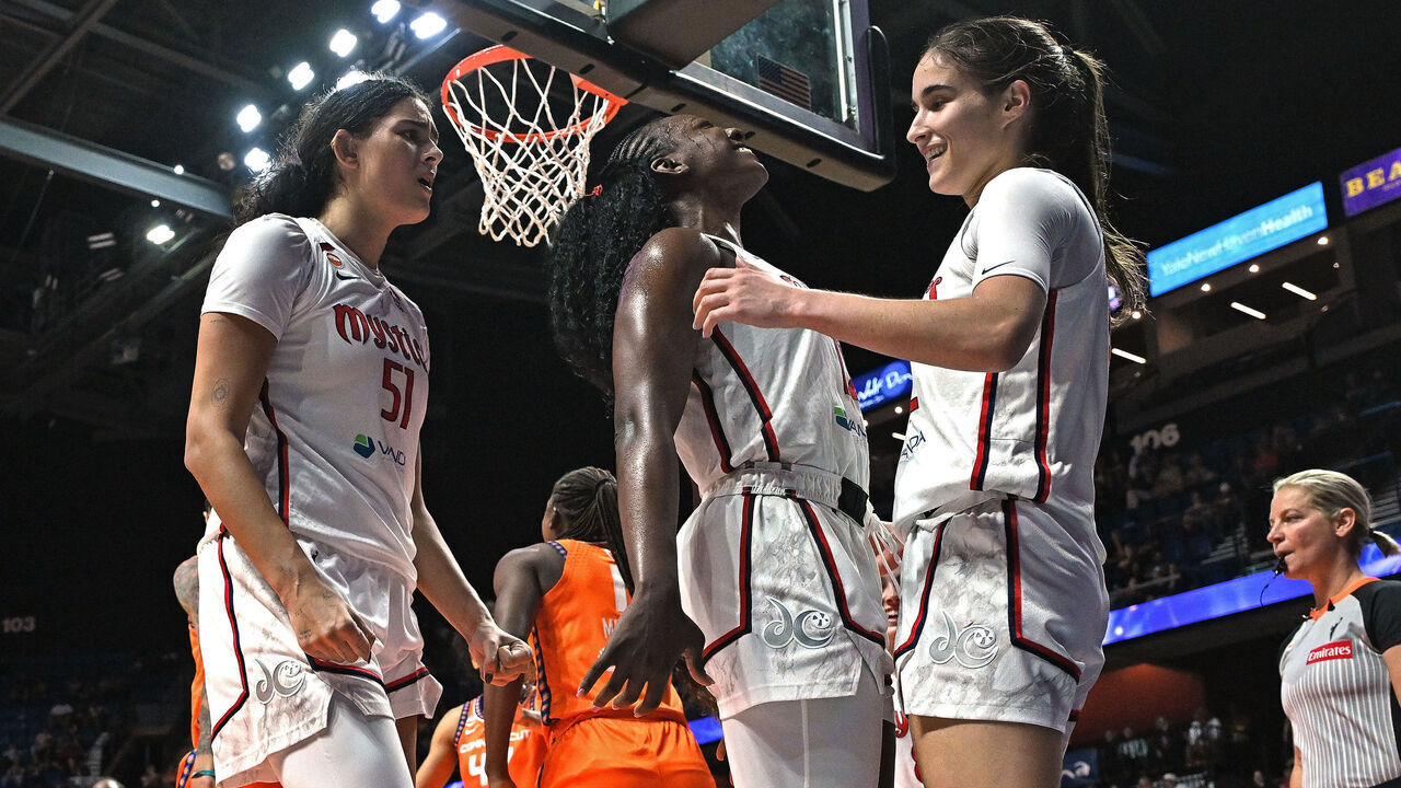 UNCASVILLE, CONNECTICUT - JUNE 17: Michaela Onyenwere #12 and Lauren Betts #51 of the Washington Mystics race to congratulate teammate Sonia Citron #22 after a basket and foul against the Connecticut Sun in the fourth quarter at Mohegan Sun Arena on June 17, 2026 in Uncasville, Connecticut.