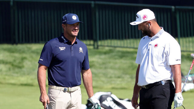 NEWTOWN, PENNSYLVANIA - MAY 12: Bryson DeChambeau of the United States and Jon Rahm of Spain looks on from the practice chipping area during a practice round prior to the PGA Championship at Aronimink Golf Club on May 12, 2026 in Newtown, Pennsylvania.