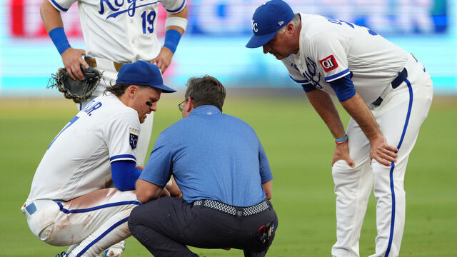 KANSAS CITY, MISSOURI - JUNE 18: Bobby Witt Jr. #7 of the Kansas City Royals is attended to by a team trainer and manager Matt Quatraro #33 after making a play against the St. Louis Cardinals in the fourth inning at Kauffman Stadium on June 18, 2026 in Kansas City, Missouri.