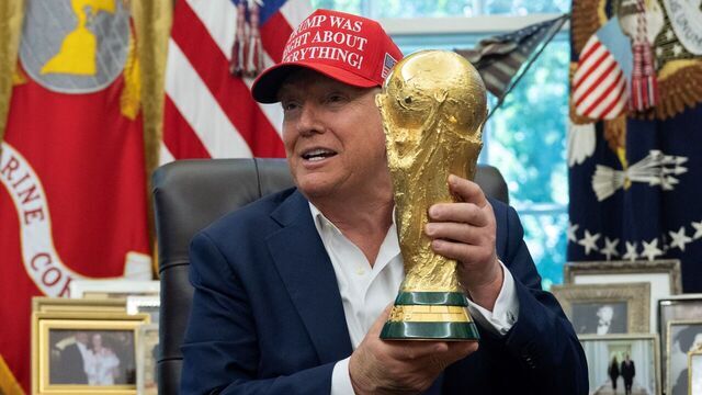US President Donald Trump holds the World Cup trophy in the Oval Office of the White House in Washington, DC, on August 22, 2025. Trump announced the 2026 World Cup draw will be held on December 5 at Washington's Kennedy Center.