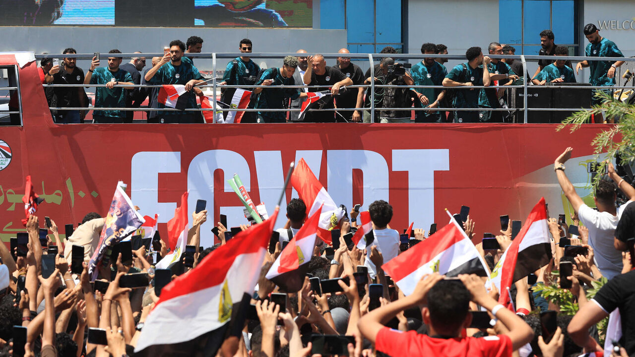 Egypt's players wave from an open-top bus as supporters gathered to welcome them at El-Alamein International Airport in the northern coastal city of El-Alamein on July 10, 2026, upon their return from the 2026 World Cup football tournament. Hundreds of euphoric supporters welcomed home Egypt's national football team in the coastal city of El-Alamein on July 10 after a historic World Cup campaign that ended with a thrilling last-16 defeat to Argentina.