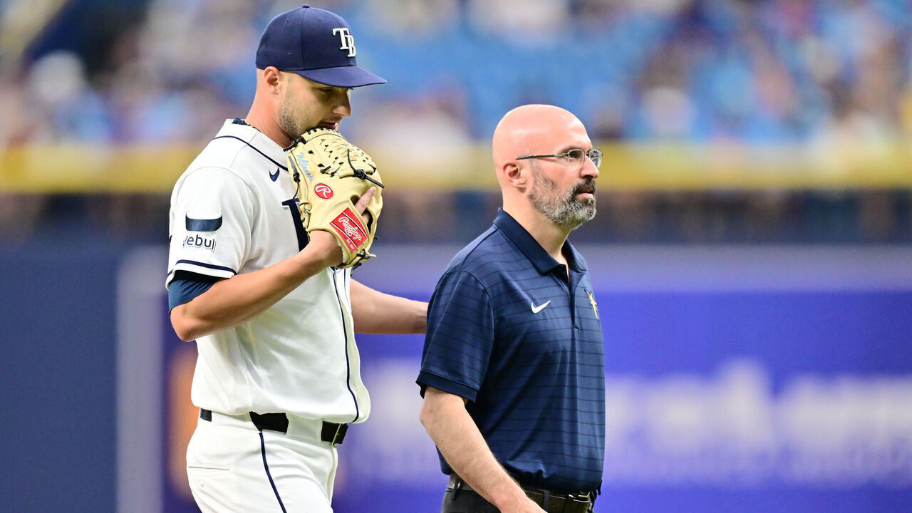 ST PETERSBURG, FLORIDA - JULY 30: Shane McClanahan #18 of the Tampa Bay Rays walks off the field with athletic trainer Joseph Benge after an injury in the fourth inning against the Texas Rangers at Tropicana Field on July 30, 2026 in St Petersburg, Florida.