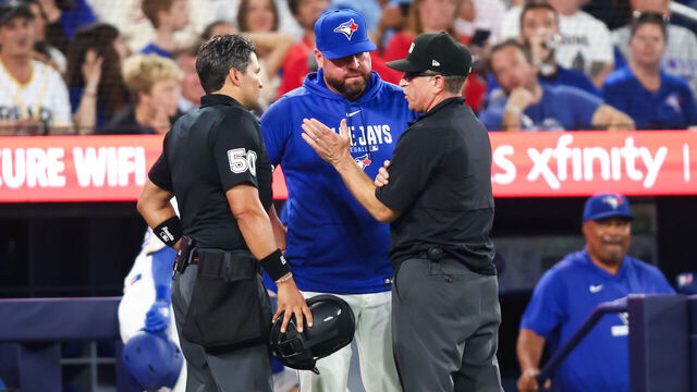 TORONTO, CANADA - AUGUST 10: Umpires explain a rule review to manager John Schneider of the Toronto Blue Jays during the seventh inning of their MLB game against the Boston Red Sox at Rogers Centre on August 10, 2026 in Toronto, Ontario, Canada.