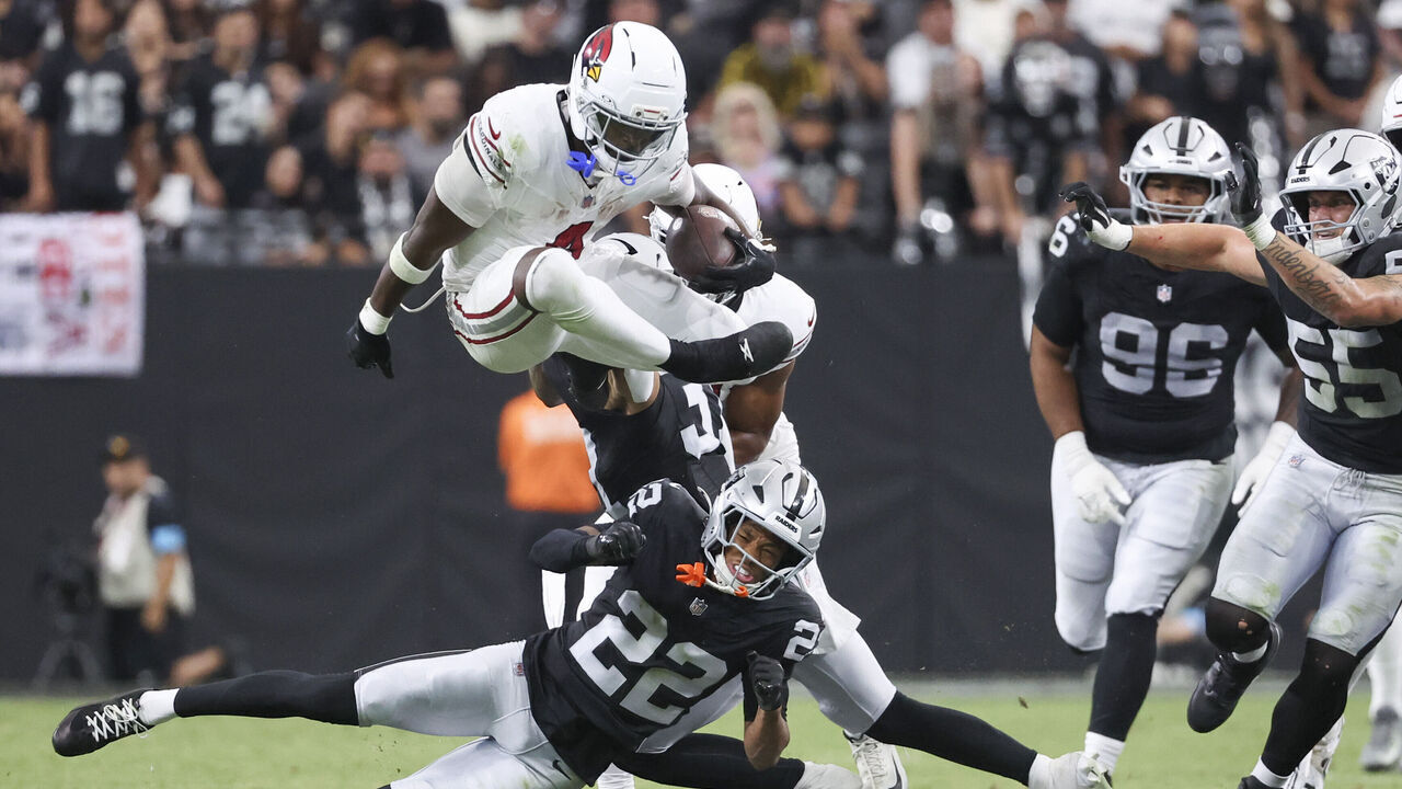 LAS VEGAS, NEVADA - AUGUST 13: Jeremiyah Love #4 of the Arizona Cardinals hurdles Greedy Vance #22 of the Las Vegas Raiders in the second quarter of the preseason game at Allegiant Stadium on August 13, 2026 in Las Vegas, Nevada.