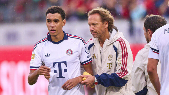 HEIDENHEIM, GERMANY - AUGUST 18: Jamal Musiala of FC Bayern München falls over during the match and requires treatment by FCB team doctor Prof. Dr. Peter Ueblacker during the preseason friendly match between 1. FC Heidenheim and FC Bayern München at Voith-Arena on August 18, 2026 in Heidenheim, Germany.