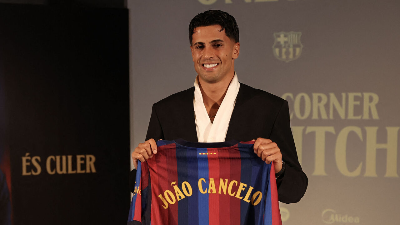 Portuguese international footballer Joao Cancelo poses with a Barcelona jersey during his official presentation as FC Barcelona's new player at the Nou Camp in Barcelona on August 20, 2026.