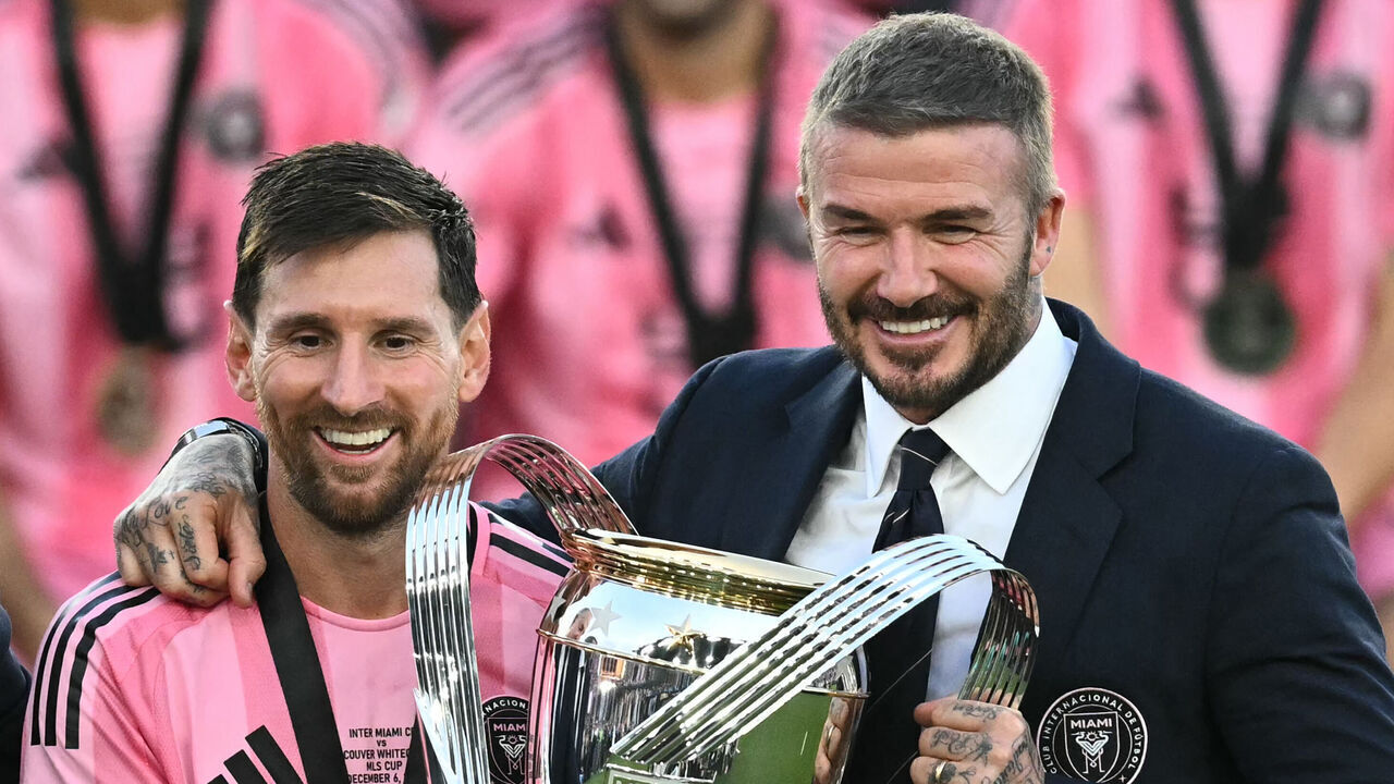TOPSHOT - Inter Miami's Argentine forward #10 Lionel Messi (L) poses with the trophy next to the team's owner David Beckham (R) after winning the Major League Soccer (MLS) Cup final between Inter Miami and the Vancouver Whitecaps at Chase Stadium in Fort Lauderdale, Florida, on December 6, 2025.
