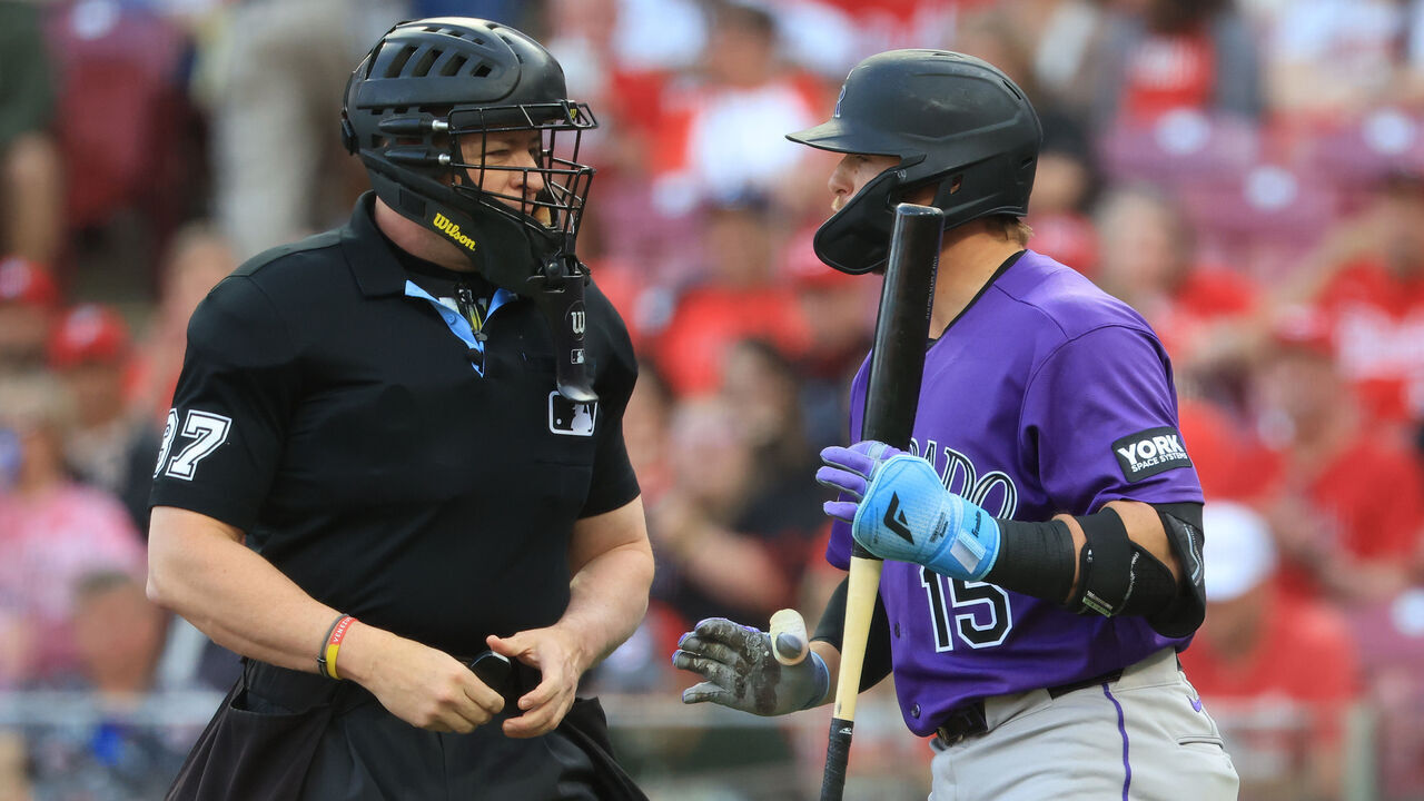 CINCINNATI, OHIO - APRIL 28: Hunter Goodman #15 of the Colorado Rockies exchanges words with home plate umpire Carlos Torres #37 during the first inning against the Cincinnati Reds at Great American Ball Park on April 28, 2026 in Cincinnati, Ohio.