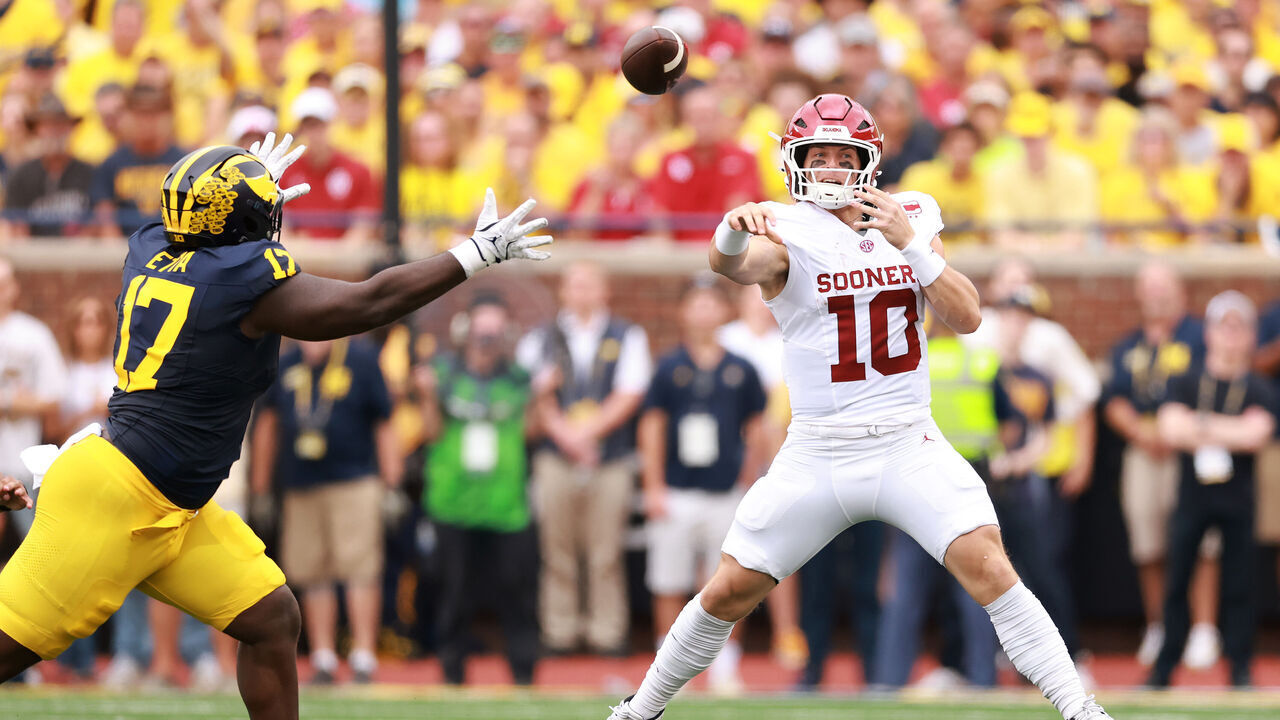ANN ARBOR, MICHIGAN - SEPTEMBER 12: John Mateer #10 of the Oklahoma Sooners throws a first half pass around Enow Etta #17 of the Michigan Wolverines at Michigan Stadium on September 12, 2026 in Ann Arbor, Michigan.