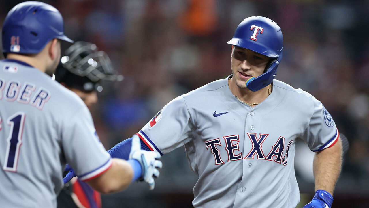 PHOENIX, ARIZONA - SEPTEMBER 12: Wyatt Langford #36 of the Texas Rangers high fives Jake Burger #21 after hitting a solo home run against the Arizona Diamondbacks during the fifth inning of the MLB game at Chase Field on September 12, 2026 in Phoenix, Arizona.