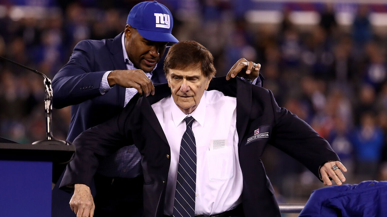 EAST RUTHERFORD, NJ - NOVEMBER 14: Former Defensive End Michael Strahan puts a coat on 2016 Giants Ring of Honor Inductee Ernie Accorsi during the halftime ceremony of the game between the Cincinnati Bengals and the New York Giants at MetLife Stadium on November 14, 2016 in East Rutherford, New Jersey.
