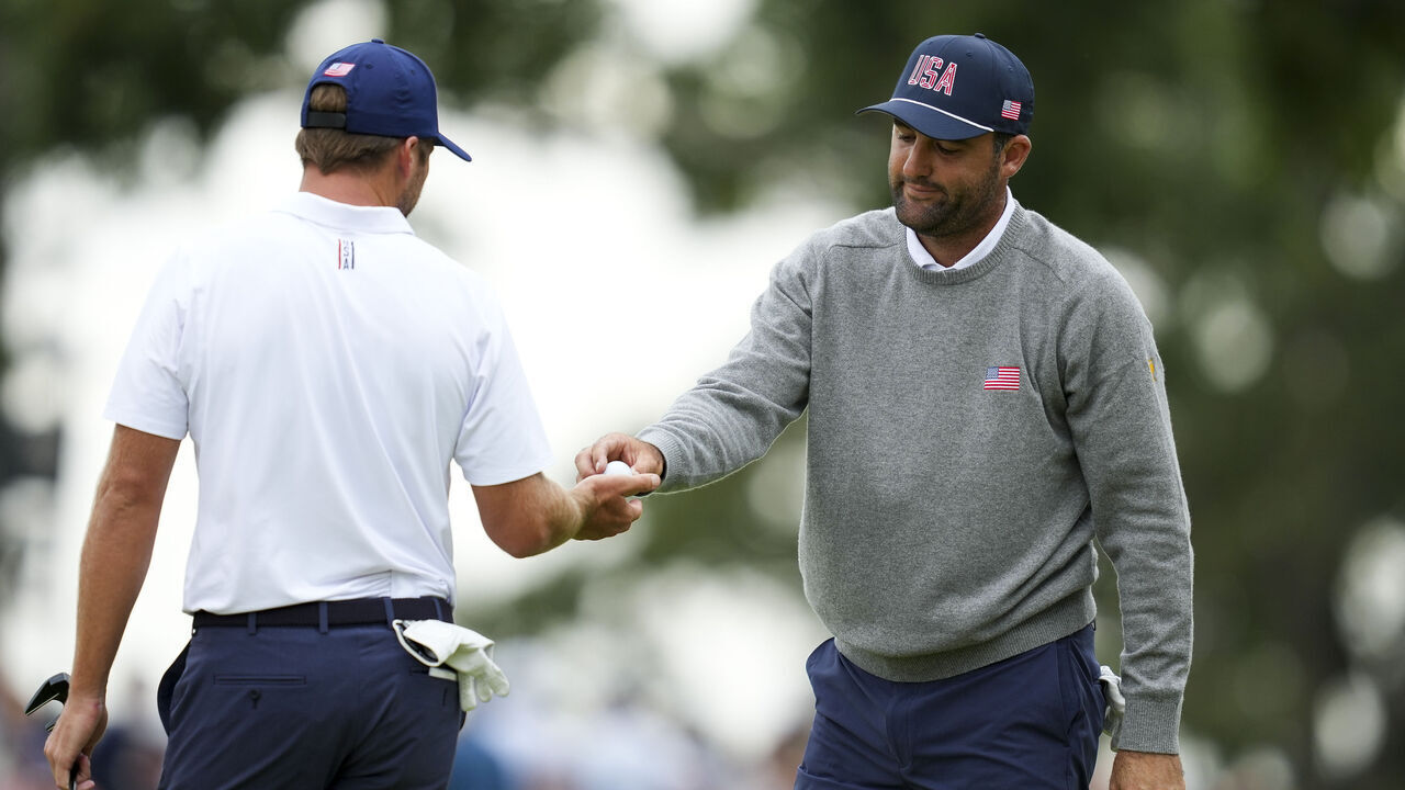 CHICAGO, ILLINOIS - SEPTEMBER 25: Scottie Scheffler of the U.S. Team hands a ball to teammate Sam Burns while playing the sixth hole during Day Two of the Presidents Cup at Medinah Country Club Course No. 3 on September 25, 2026 in Chicago, Illinois.
