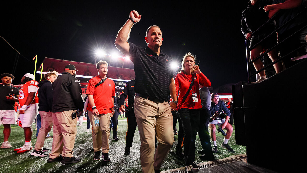 PISCATAWAY, NEW JERSEY - SEPTEMBER 25: Greg Schiano of the Rutgers Scarlet Knights walks off the field with his wife, Christy Schiano, after recording his 100th win with the program against the Howard Bison at SHI Stadium on September 25, 2026 in Piscataway, New Jersey. The Rutgers Scarlet Knights defeated the Howard Bison 58-7.