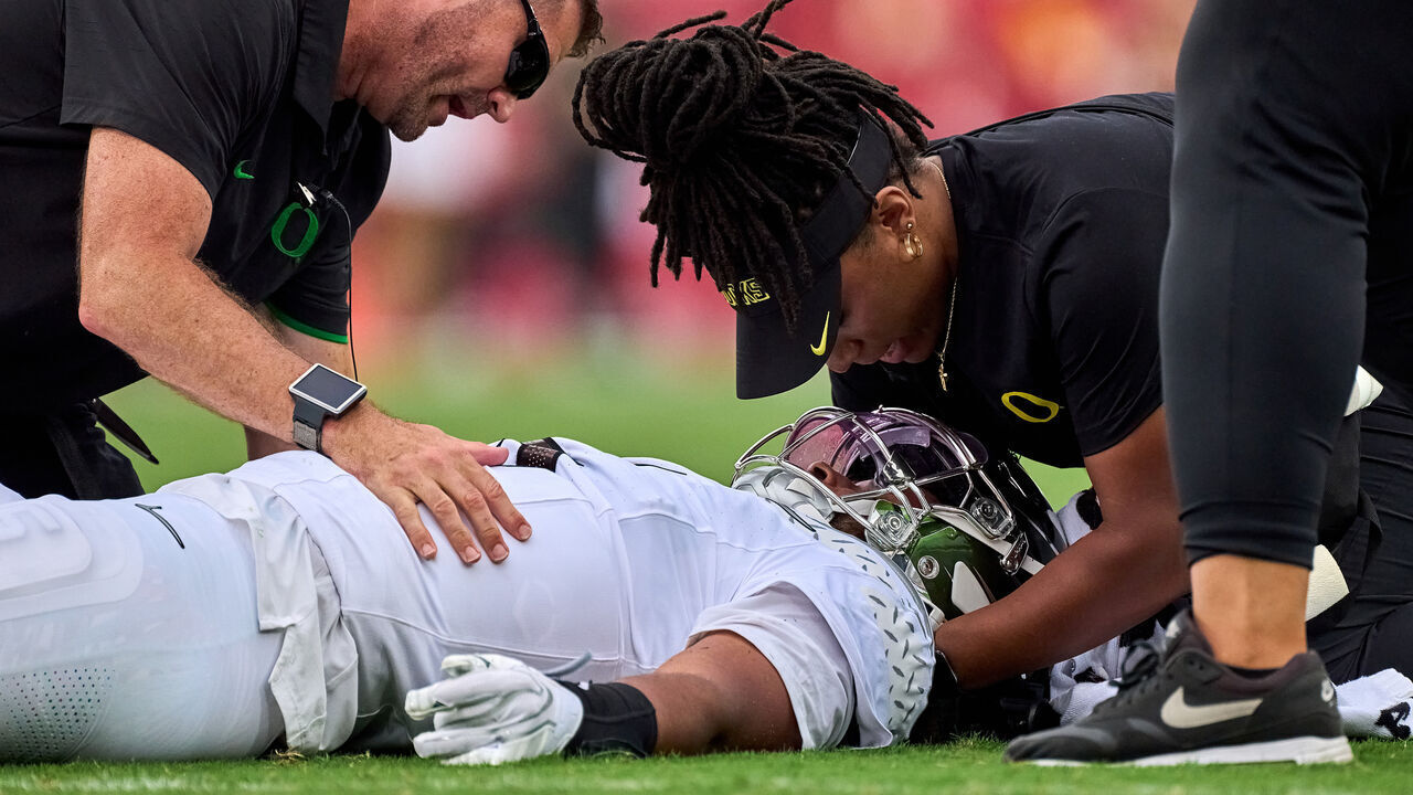 LOS ANGELES, CALIFORNIA - SEPTEMBER 26: Oregon Ducks medical staff attends to an injured Quarterback Dante Moore (5) of the Oregon Ducks who was targeted in a tackle by linebacker Desman Stephens II (8) of the USC Trojans in action during a game between the Oregon Ducks and the USC Trojans at Los Angeles Memorial Coliseum on September 26, 2026 in Los Angeles, California.