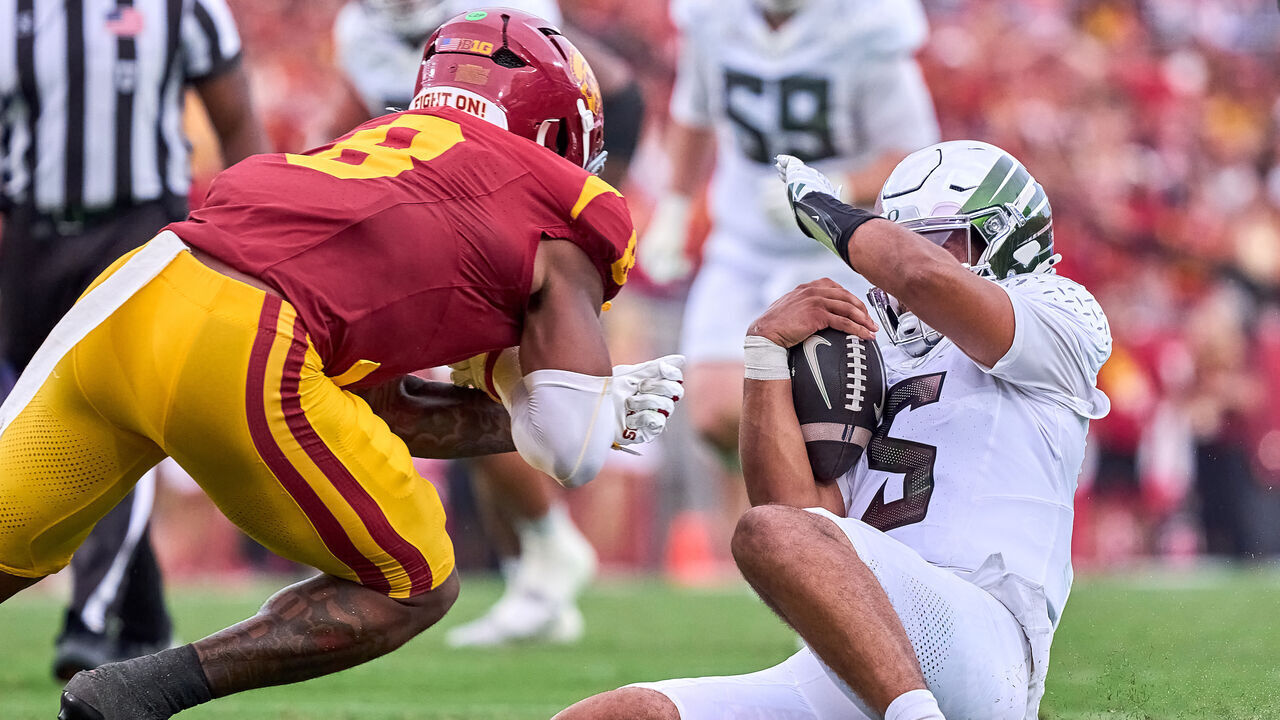LOS ANGELES, CALIFORNIA - SEPTEMBER 26: Quarterback Dante Moore (5) of the Oregon Ducks runs with the football and slides to avoid a tackle from linebacker Desman Stephens II (8) of the USC Trojans in action during a game between the Oregon Ducks and the USC Trojans at Los Angeles Memorial Coliseum on September 26, 2026 in Los Angeles, California.