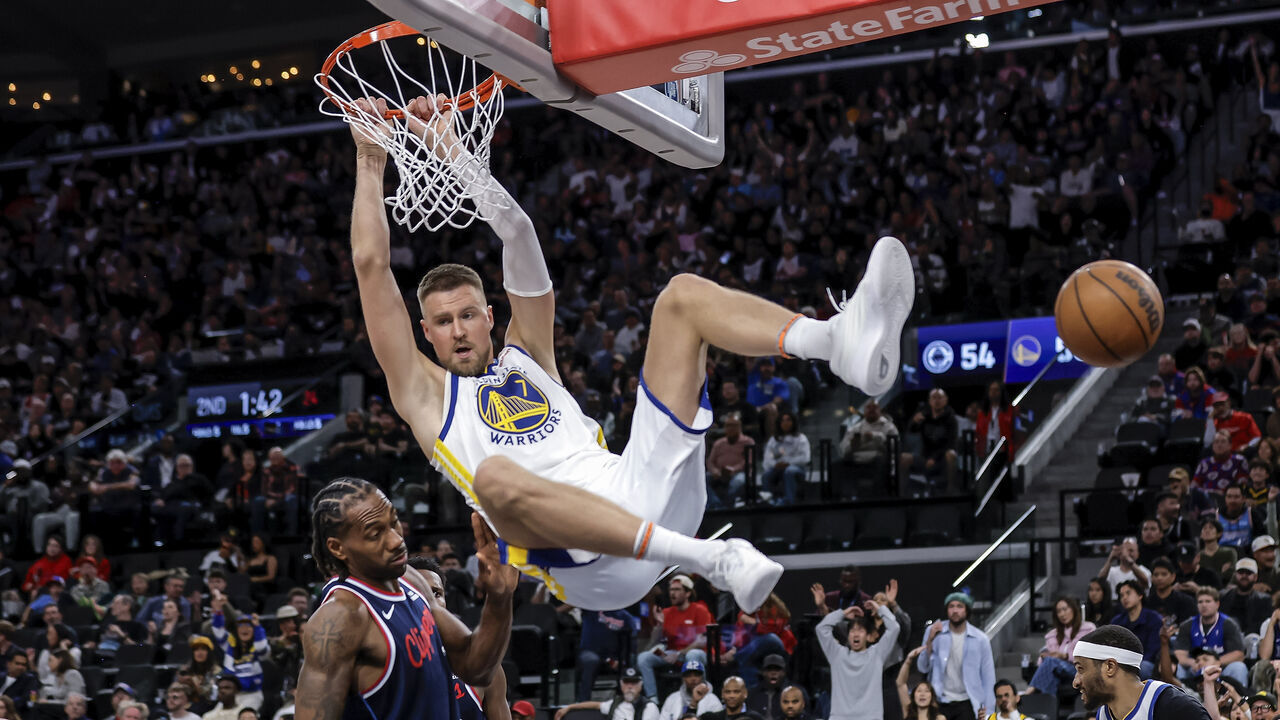 Krystaps Porzingis (7) hangs from the rim after following a missed Stephen Curry (30) shot attemps with a dunk in the first half as the Golden State Warriors played the Los Angeles Clippers in an NBA play-in tournament game at Intuit Dome in Inglewood, Calif., on Wednesday, April 15, 2026.