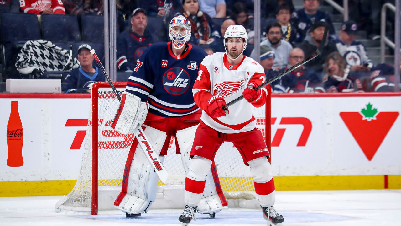 WINNIPEG, CANADA - JANUARY 24: Goaltender Connor Hellebuyck #37 of the Winnipeg Jets and Dylan Larkin #71 of the Detroit Red Wings keeps an eye on the play during third period action at the Canada Life Centre on January 24, 2026 in Winnipeg, Manitoba, Canada. The Wings defeated the Jets 5-1.