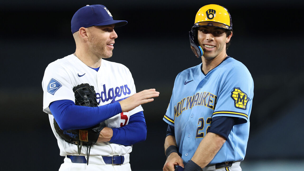 LOS ANGELES, CALIFORNIA - AUGUST 13: Freddie Freeman #5 of the Los Angeles Dodgers laughs with Christian Yelich #22 of the Milwaukee Brewers during the fourth inning at Dodger Stadium on August 13, 2026 in Los Angeles, California.