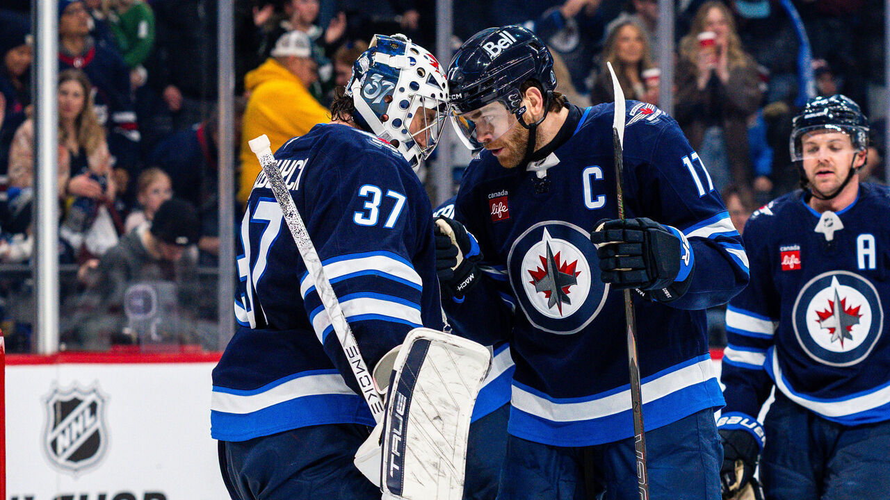 WINNIPEG, CANADA - JANUARY 11: Connor Hellebuyck #37 of the Winnipeg Jets and Adam Lowry #17 of the Winnipeg Jets celebrate a 4-3 win over the New Jersey Devils at Canada Life Centre on January 11, 2026 in Winnipeg, Canada.