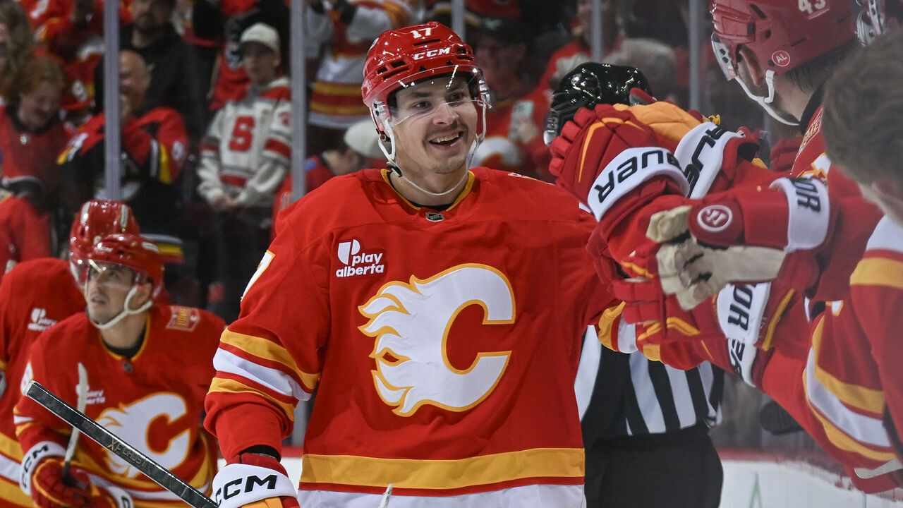 CALGARY, AB - OCTOBER 18: Yegor Sharangovich #17 of the Calgary Flames celebrates with teammates Morgan Frost #16, Aydar Suniev #61 after a goal against the Carolina Hurricanes at Scotiabank Saddledome on October 18, 2026 in Calgary, Alberta, Canada.