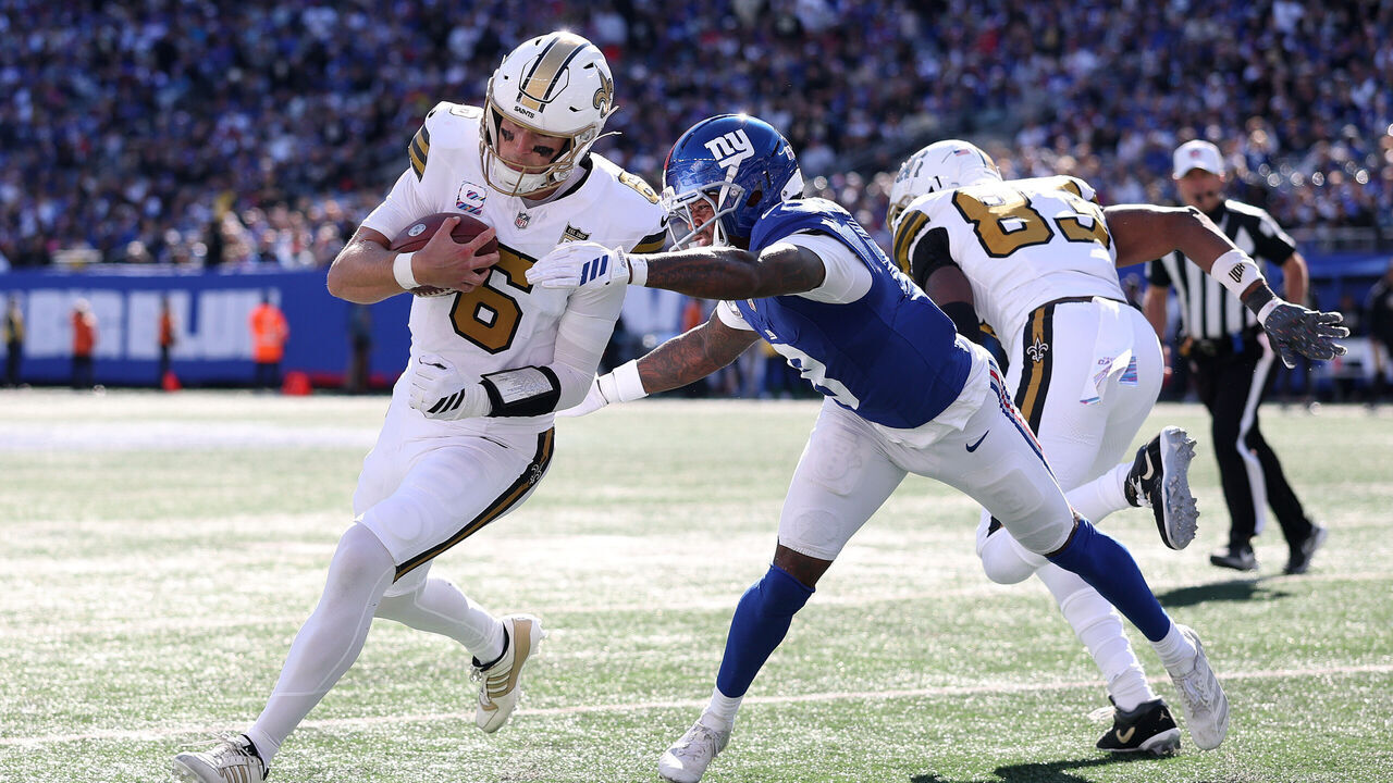 EAST RUTHERFORD, NEW JERSEY - OCTOBER 18: Tyler Shough #6 of the New Orleans Saints scrambles with the ball under pressure from Jevon Holland #8 of the New York Giants during the second quarter at MetLife Stadium on October 18, 2026 in East Rutherford, New Jersey.