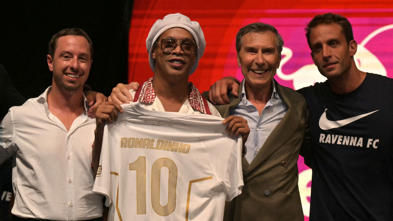 Newly recruited Brazilian football player Ronaldinho poses on stage with the jersey of Ravenna FC next to the president of the club, Ignazio Cipriani (R) during the team presentation in Marina di Ravenna on August 20, 2026. Former Ballon d'Or and World Cup winner Ronaldinho is set to come out of retirement aged 46 to play for Ravenna in the Italian third tier.