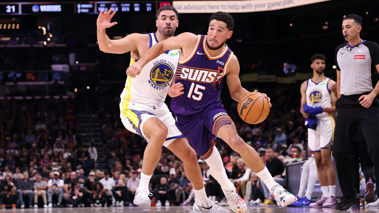 PHOENIX, ARIZONA - OCTOBER 24: Devin Booker #15 of the Phoenix Suns drives to the basket against Georges Niang #32 of the Golden State Warriors during the first half at Mortgage Matchup Center on October 24, 2026 in Phoenix, Arizona.